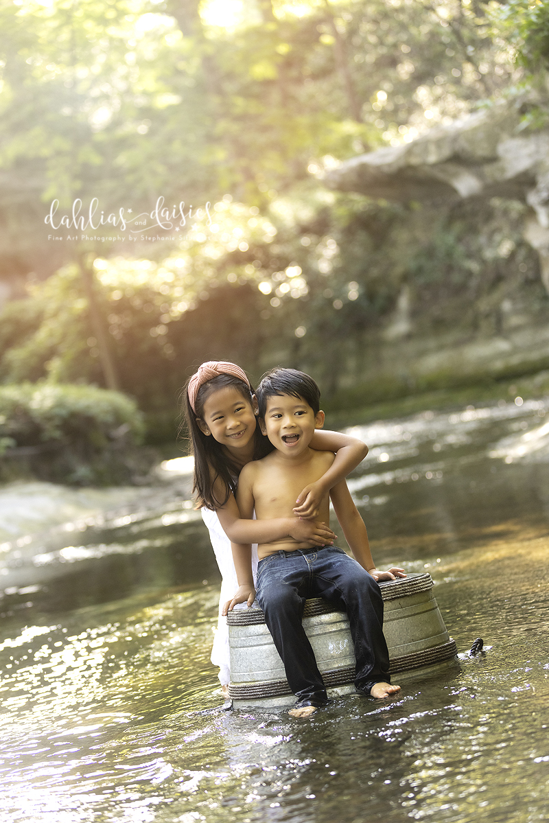 Siblings hug while sitting in creek