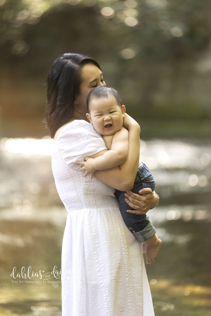 Mother embraces baby in creek during family photography session