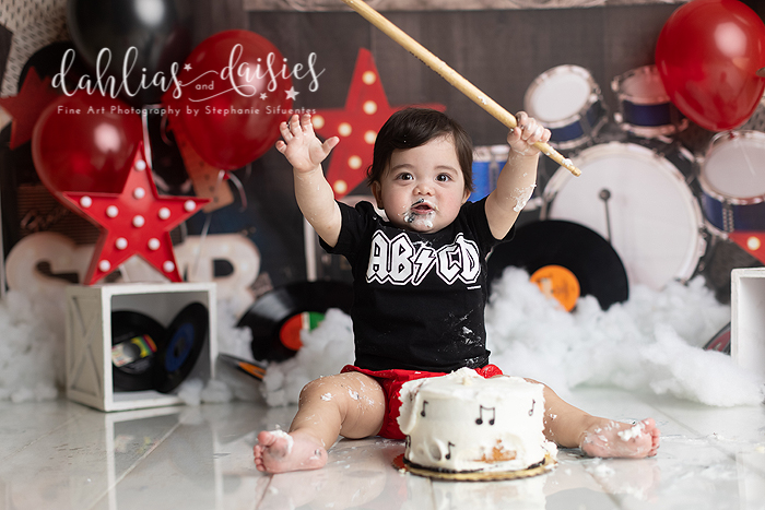Baby plays with drum sticks and cake
