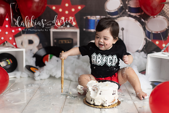 Baby eats cake at first birthday photography session.
