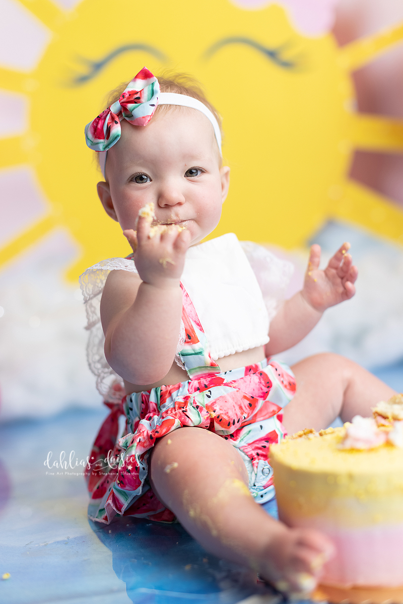 Baby girl eating cake at her 1st birthday photo session


