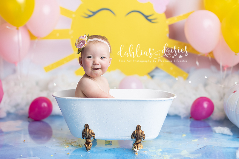 11 month old girl splashing in tub at her 1st birthday photoshoot