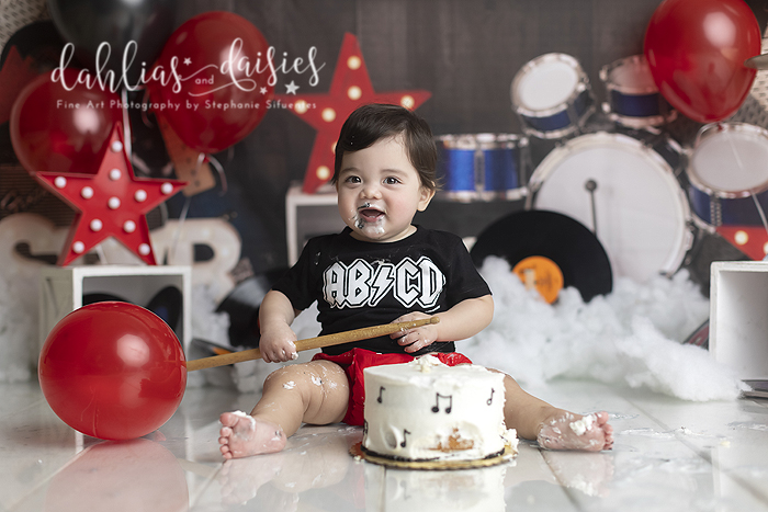 Baby eating cake at first birthday cake smash photography session.