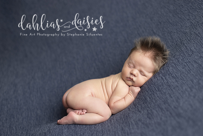 Newborn boy posed on blue fabric