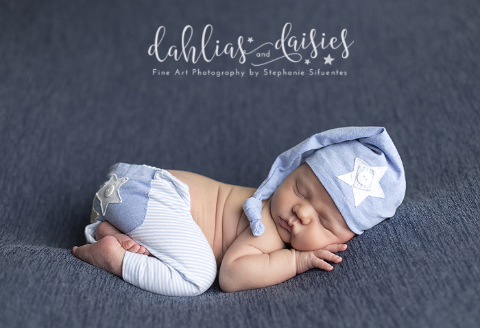 Newborn boy snuggled on blue fabric