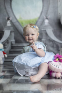 Baby girl holds up one finger at her 1st birthday photoshoot