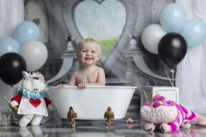Baby girl laughs in tub at Alice in Wonderland cake smash
