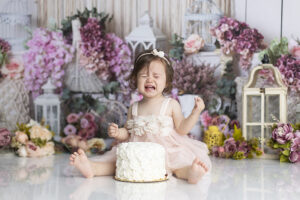 11 month old girl making funny face after tasting cake