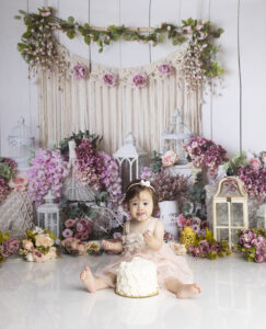 12 month old girl eating cake at her first birthday photoshoot
