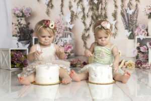 Twin girls eat cake at their floral themed cake smash