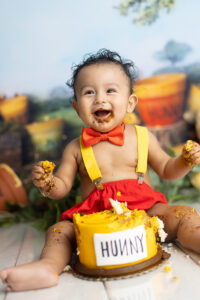 12 month old smiles big at his Winnie the Pooh cake smash