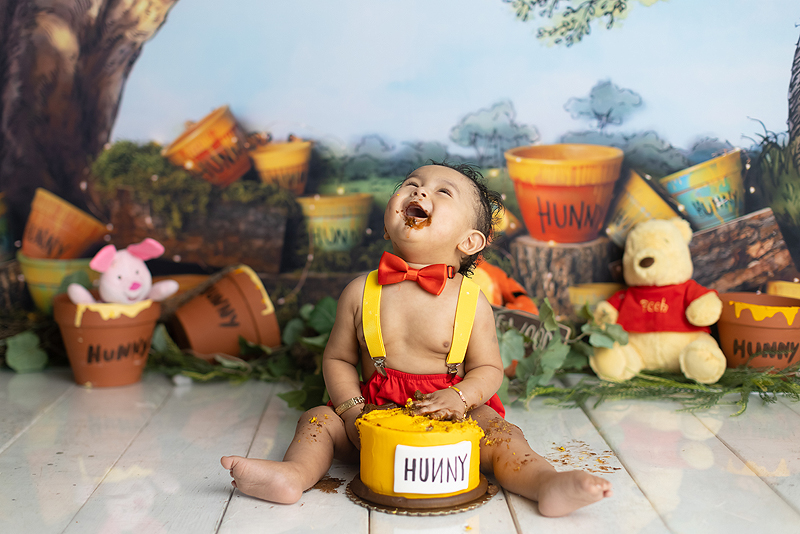 Baby laughs while eating cake at his 1st birthday photoshoot