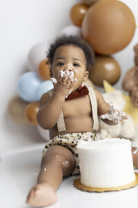 Baby boy eats cake at his teddy bear themed cake smash