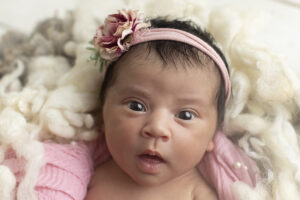 Newborn girl stares int the camera at newborn photosession