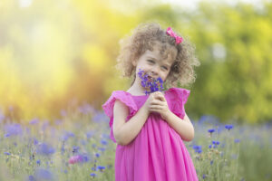 young girl smells wildflowers