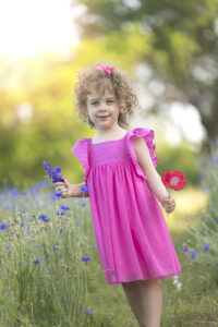 Girl wearing pink dress stands in a Wildflower field