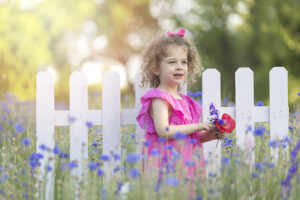 Young girl holds wildflowers in a large field of flowers