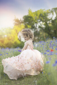 Beautiful young girl with curly hair plays in wildflower field