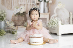 12 month old girl eats cake at her 1st birthday photoshoot