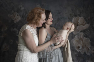 Mother and grandmother admire newborn boy at newborn photoshoot