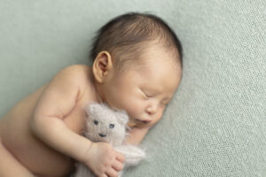 Newborn boy snuggles teddy bear