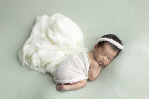 Newborn girl posed on green fabric at her newborn photoshoot