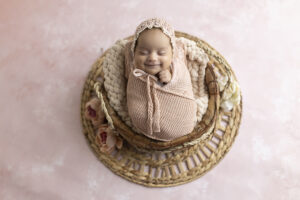 Newborn girl smiles at her newborn photoshoot