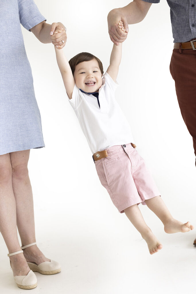 Parents swing young son into the air at family photoshoot