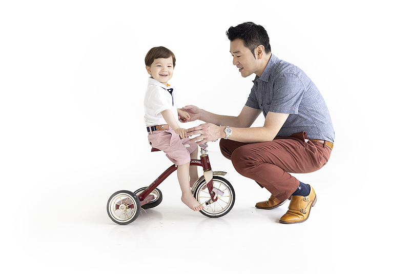 Father and son play with vintage tricycle