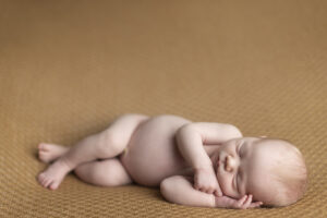 Newborn boy laying on golden colored fabric