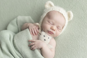 Newborn boy snuggles teddy bear