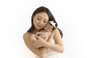 Mother snuggles newborn girl to her face at newborn photography shoot