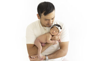 New father holds newborn girl at newborn photography shoot