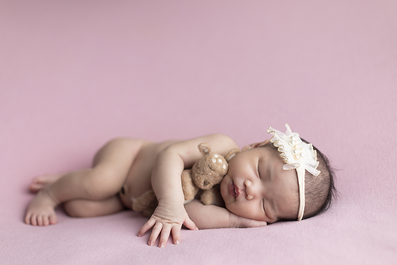 Newborn girl laying on side with felted deer at her newborn session
