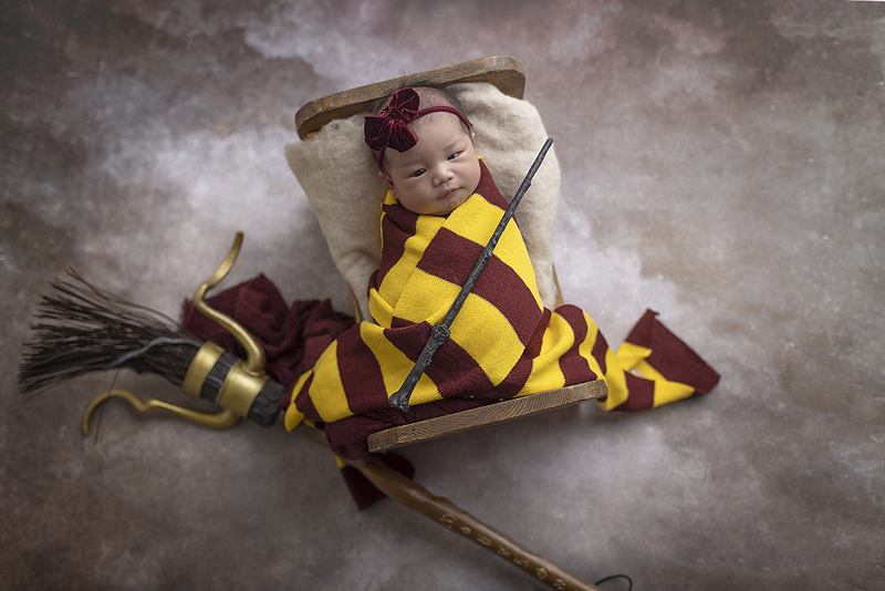 Newborn girl in in Harry Potter scarf and props