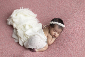 Newborn girl on pink fabric and flowing white scaarves