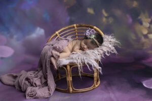 Newborn girl snuggled up on purple fur at her newborn photoshoot