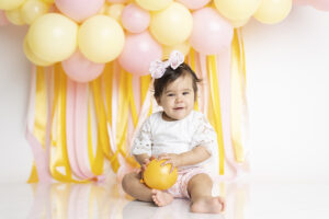 Baby girl smiling at her cake smash photography session