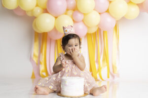 12 month old girl eating cake at her cake smash photography session