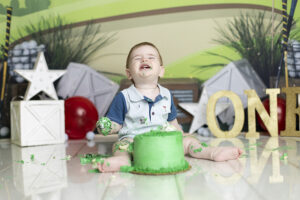 Baby boy plays in cake at golf themed cake smash