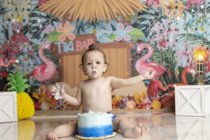 Baby boy plays with cake at his Tiki themed cake smash