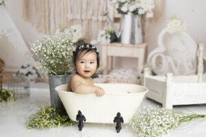 12 month old girl splashes in tub at her cake smash photography session