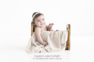 Baby relaxes in wooden bed at photography session