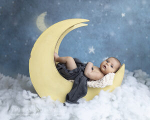 Newborn boy rests on wooden moon prop