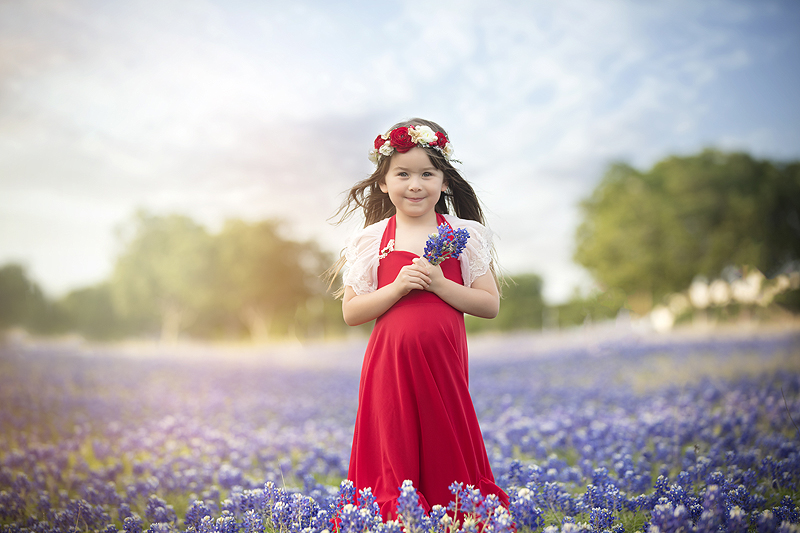 Girl in red dress stands in Dallas, Texas bluebonnet field