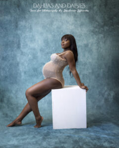 Pregnant woman poses on box at maternity photography session