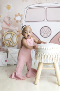 Baby girl laughs while standing at 70s themed cake smash