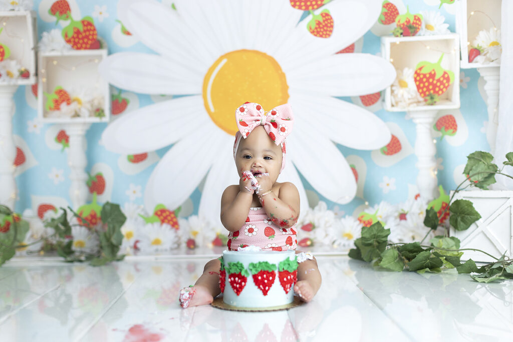 Baby girl eats strawberry themed cake