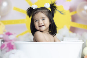 Baby smiles at camera while splashing in mini tub