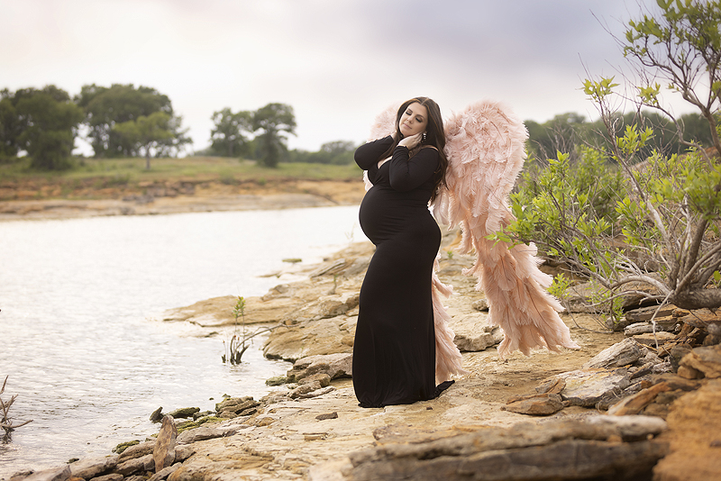 Pregnant woman wearing black dress poses for pictures